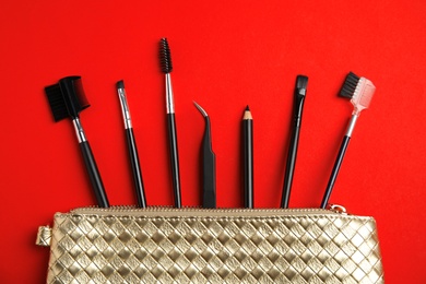 Set of professional eyebrow tools on red background, flat lay