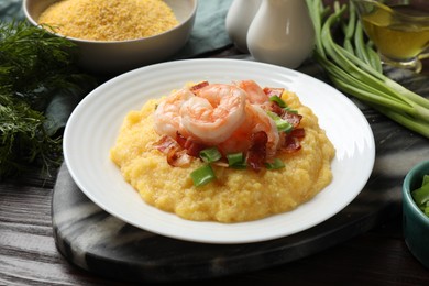 Plate with fresh tasty shrimps, bacon, grits and green onion on dark wooden table