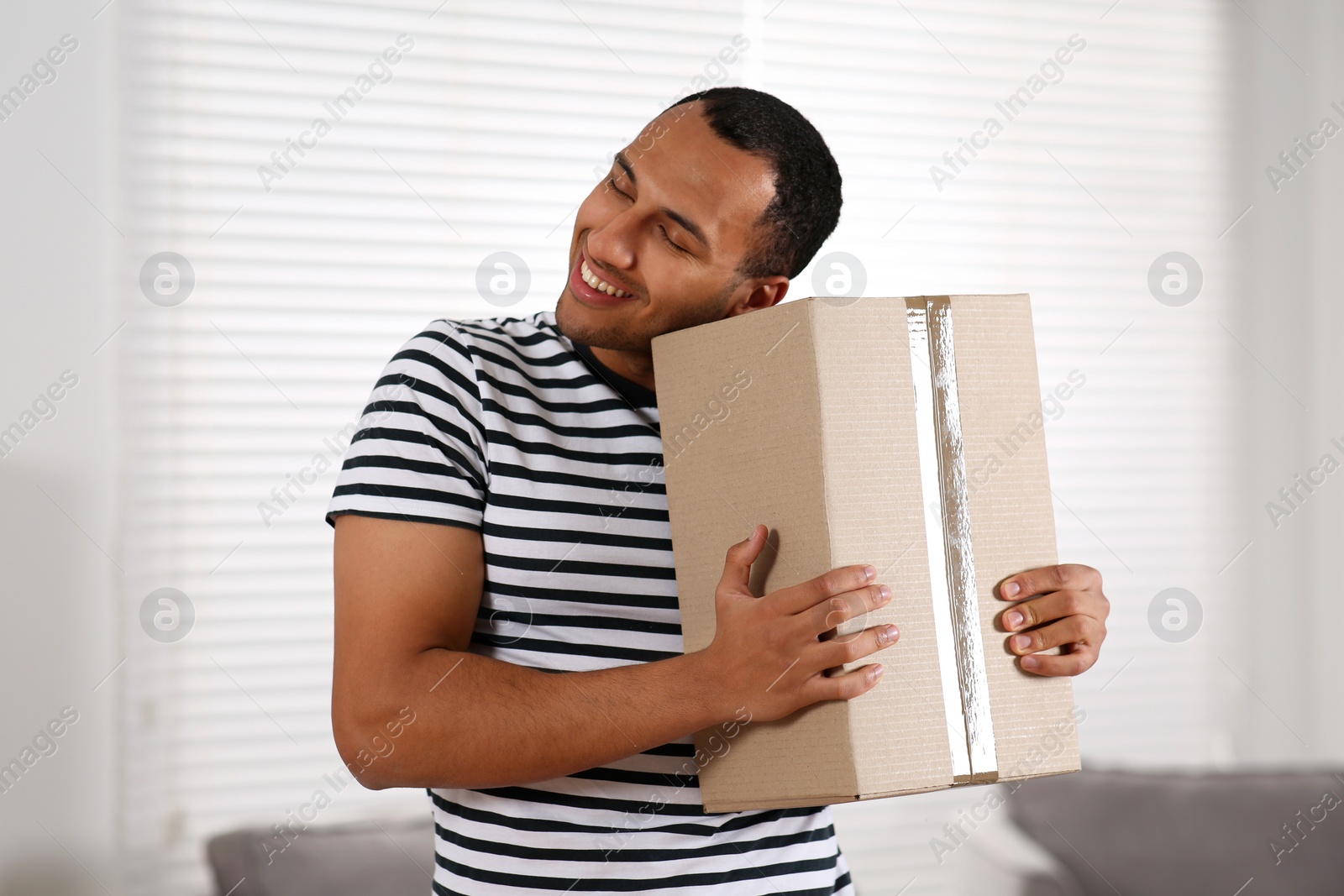 Photo of Happy young man with parcel at home. Internet shopping