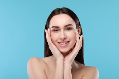 Portrait of beautiful young woman on light blue background