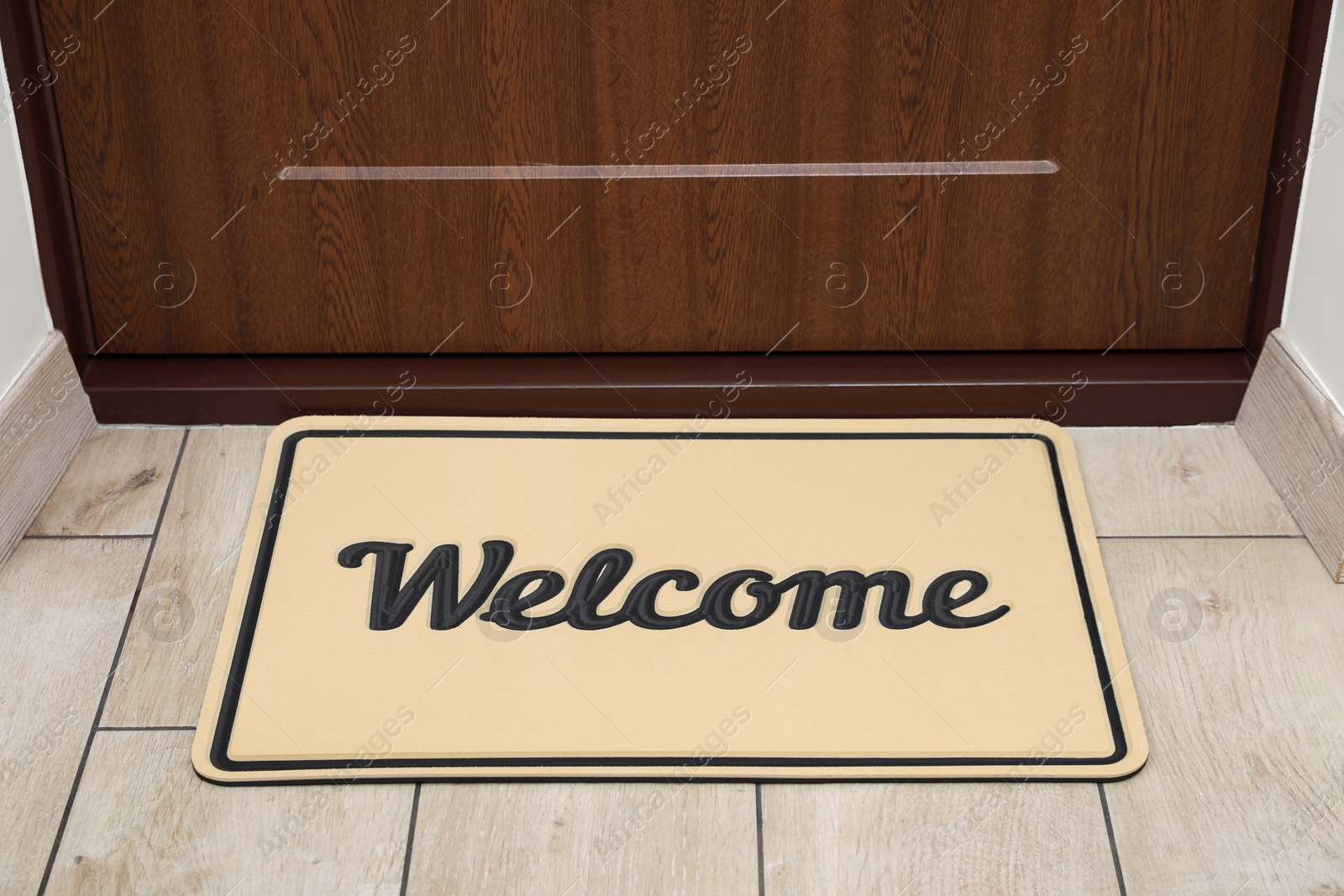 Photo of Beautiful beige doormat with word Welcome on floor near entrance