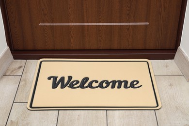 Photo of Beautiful beige doormat with word Welcome on floor near entrance