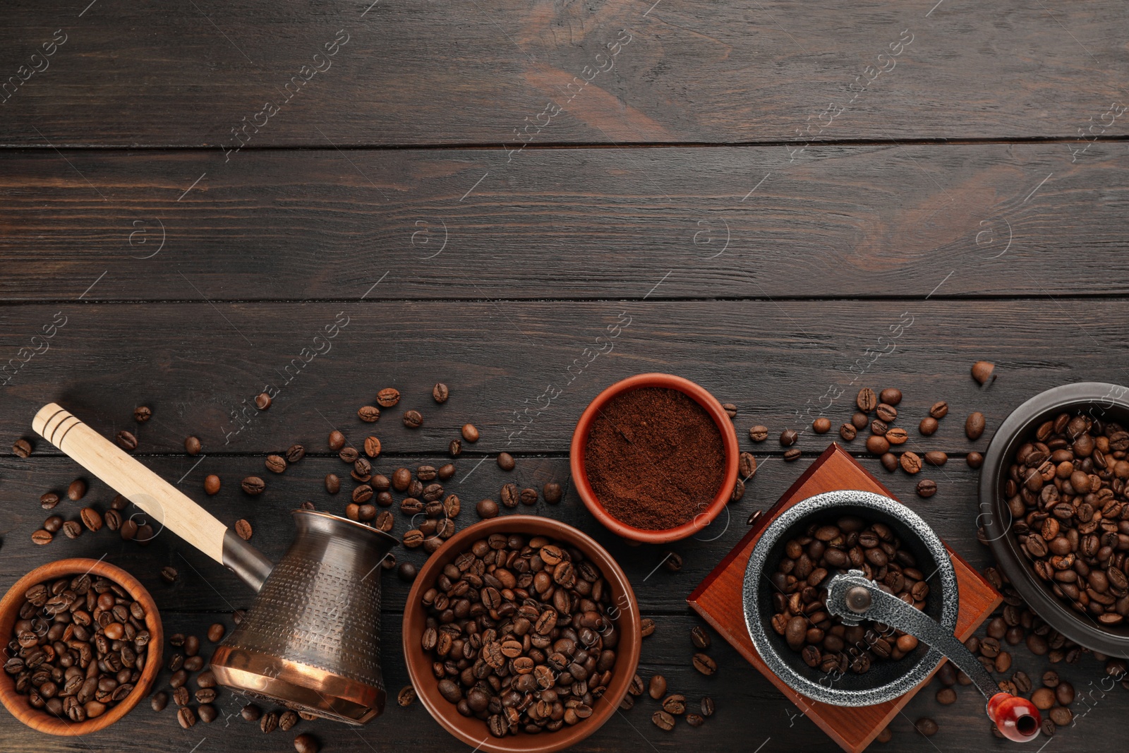 Photo of Vintage manual coffee grinder with beans, powder and jezve on wooden table, flat lay. Space for text