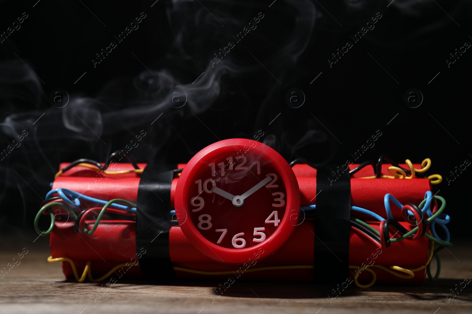 Photo of Dynamite time bomb on wooden table against black background