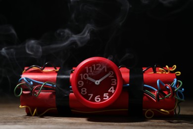 Photo of Dynamite time bomb on wooden table against black background
