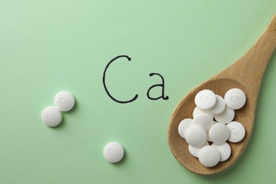 Photo of Flat lay composition with calcium supplement pills on light green background