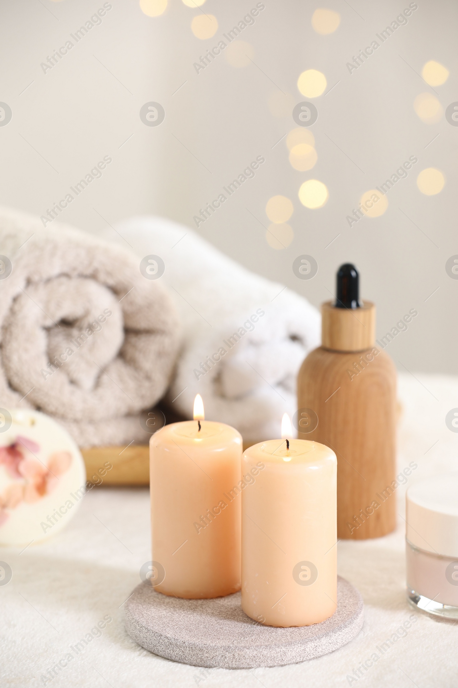 Photo of Spa composition. Burning candles and personal care products on soft white surface