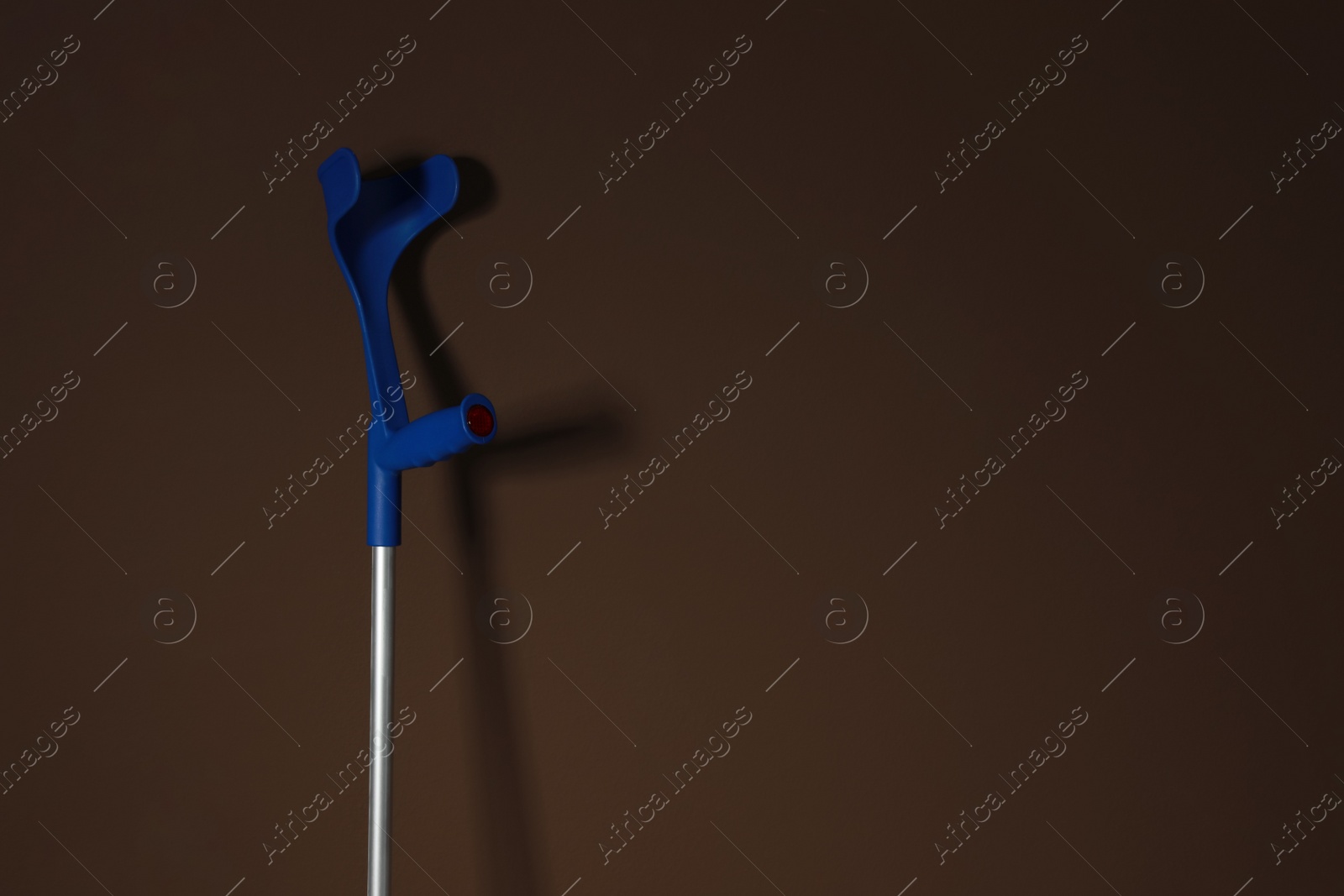 Photo of Elbow crutch on brown background. Space for text