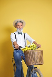 Portrait of handsome mature man with bicycle on color background