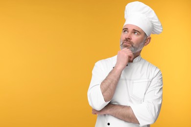 Photo of Chef in uniform on orange background, space for text