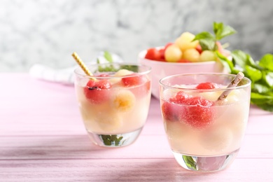 Photo of Glasses of melon and watermelon ball cocktail on pink wooden table. Space for text