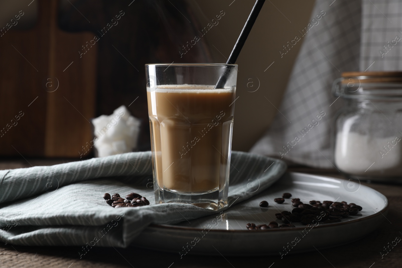 Photo of Coffee drink in glass with straw and beans on wooden table