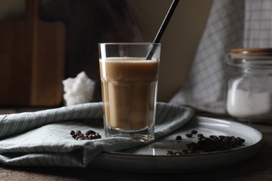 Photo of Coffee drink in glass with straw and beans on wooden table
