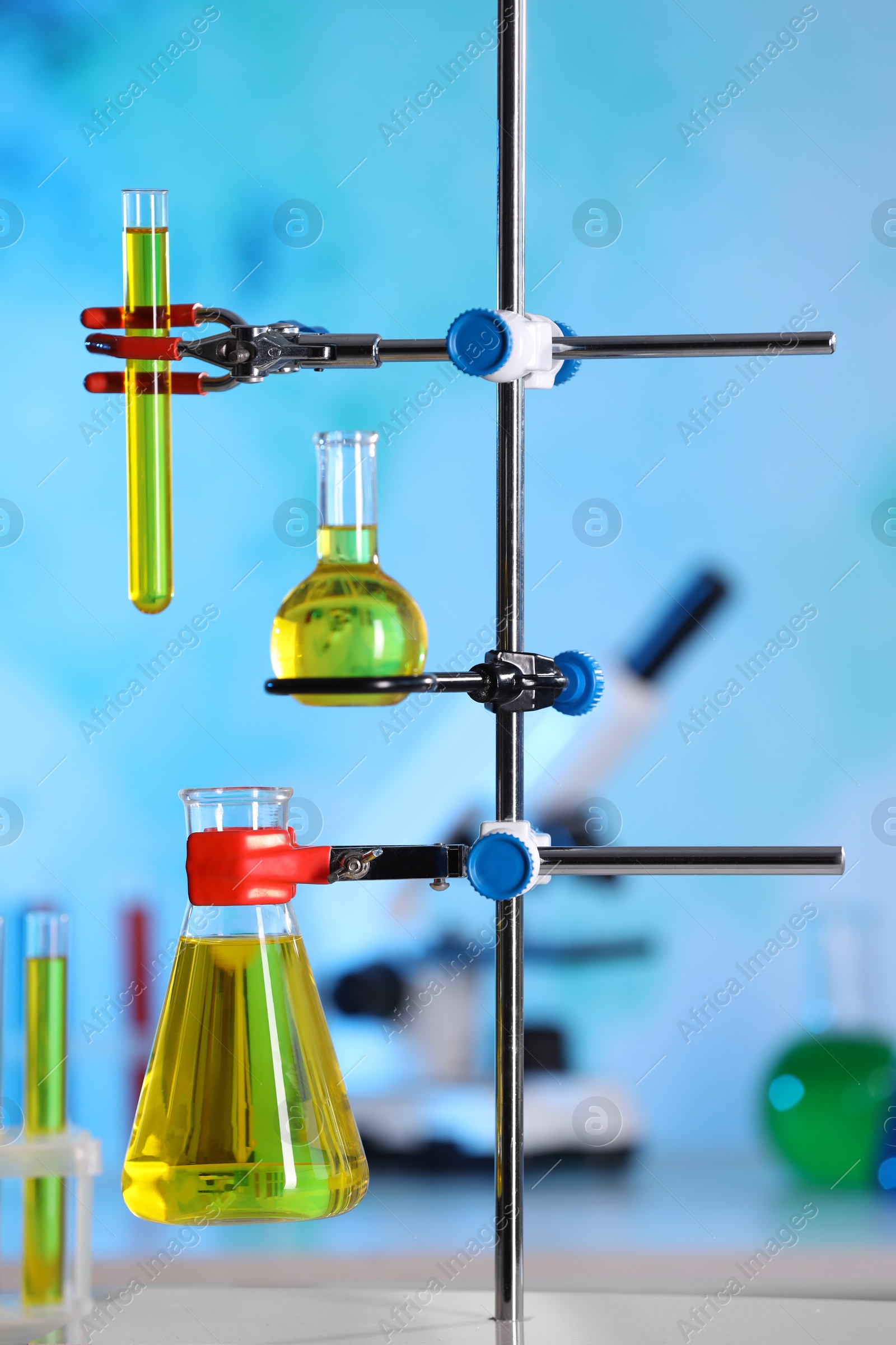 Photo of Laboratory glassware with yellow liquid on retort stand indoors