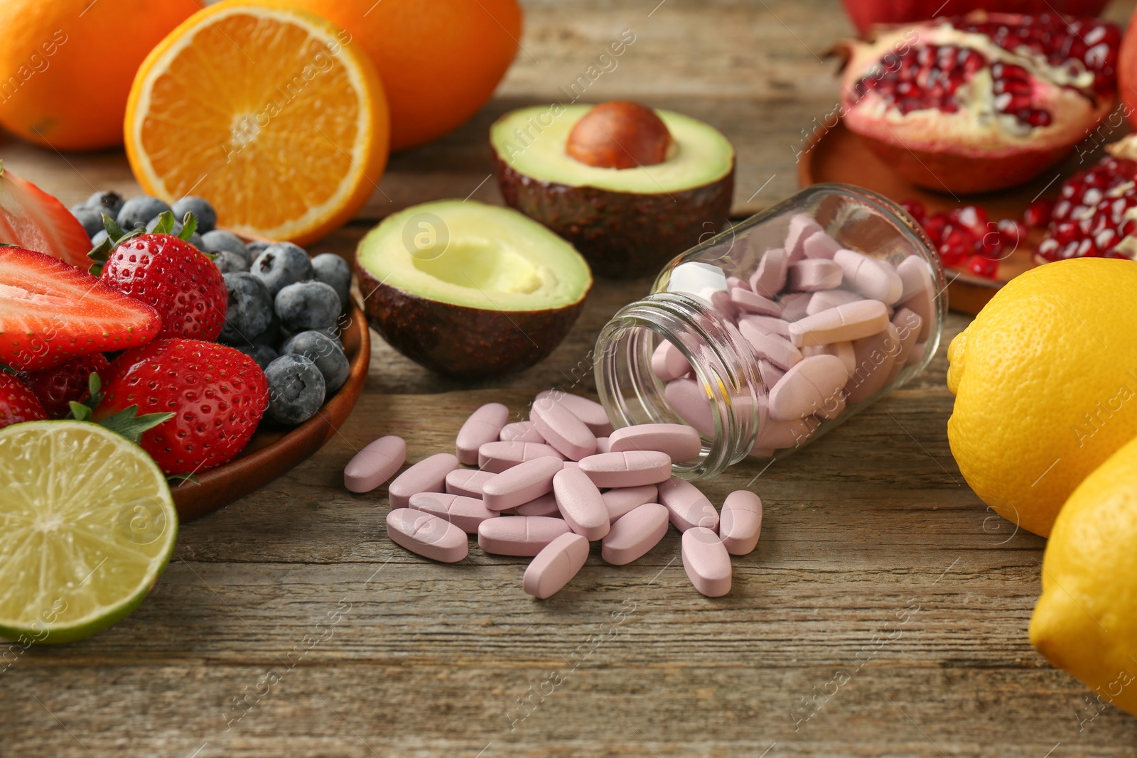 Photo of Vitamin pills in bottle and fresh fruits on wooden table