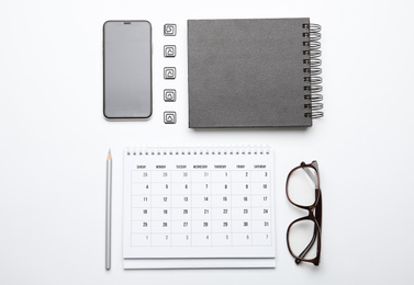 Photo of Calendar, notebook, glasses and mobile phone on white background, top view