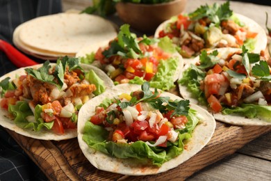 Delicious tacos with vegetables and meat on table, closeup