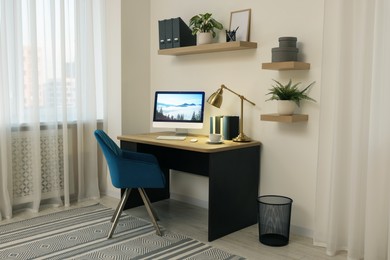 Cozy workspace with computer on wooden desk and comfortable chair at home