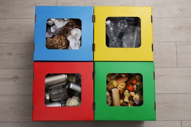 Photo of Garbage sorting. Full trash bins for separate waste collection indoors, top view