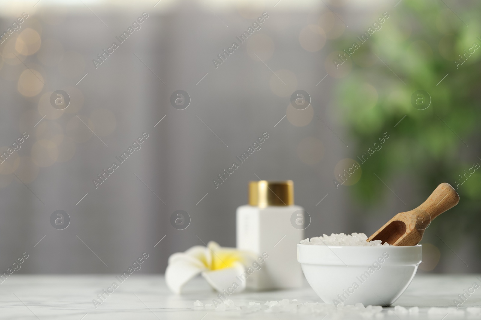 Photo of Sea salt and wooden scoop on white marble table, space for text