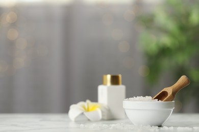 Sea salt and wooden scoop on white marble table, space for text