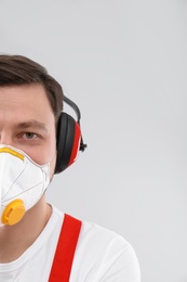 Photo of Male industrial worker in uniform on light background, space for text. Safety equipment