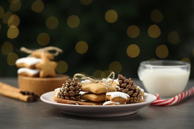 Photo of Decorated cookies and milk on grey table against blurred Christmas lights