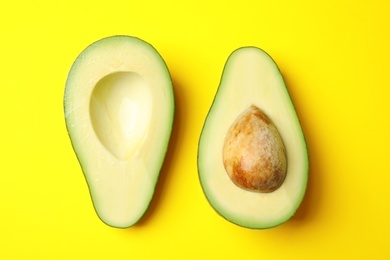 Photo of Cut fresh ripe avocado on yellow background, flat lay