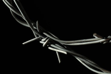 Photo of Metal barbed wire on black background, closeup