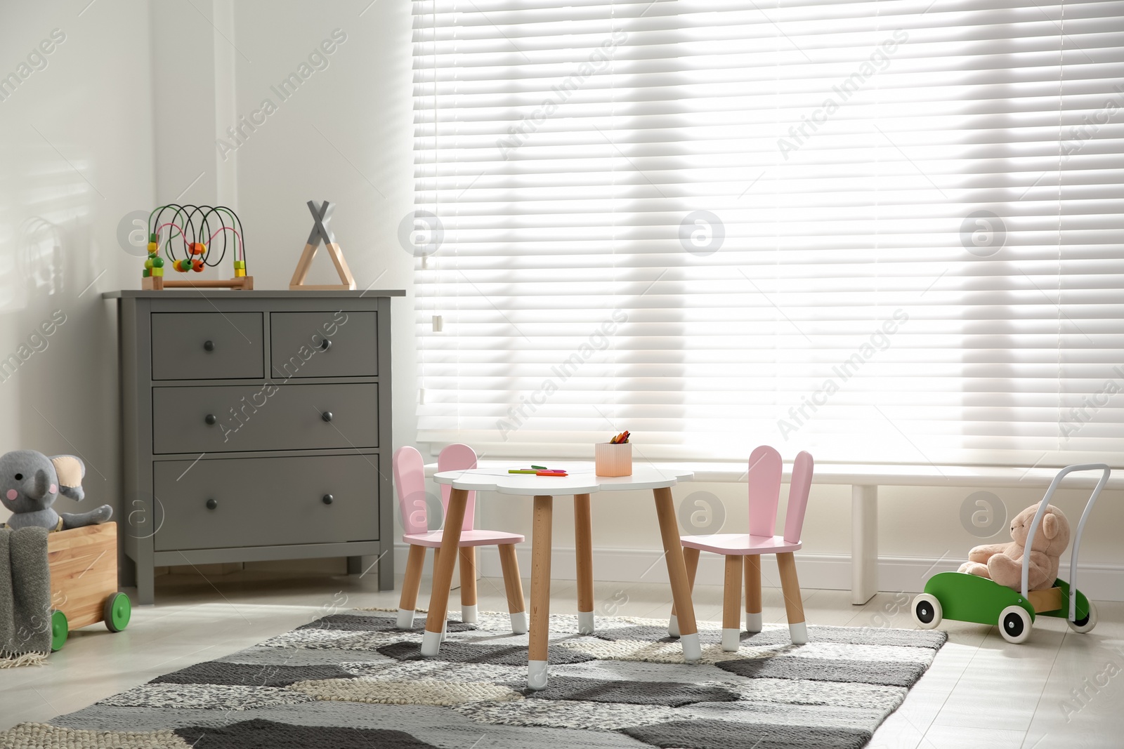 Photo of Little table and chairs with bunny ears near window in children's room. Interior design