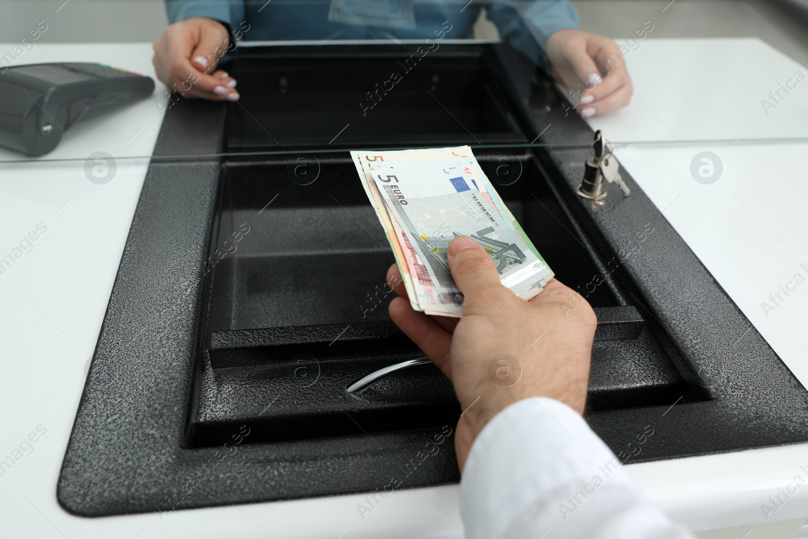 Photo of Cashier giving money to woman at currency exchange window in bank, closeup