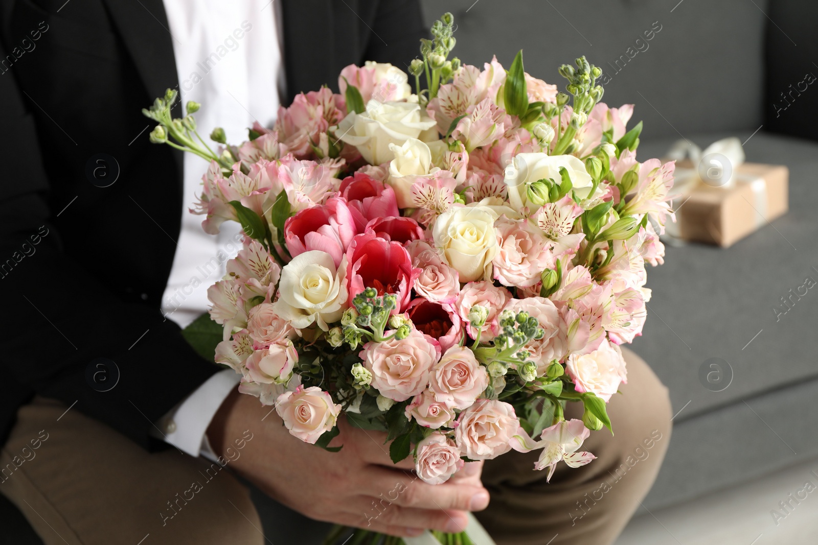 Photo of Man with beautiful bouquet of flowers on sofa indoors, closeup