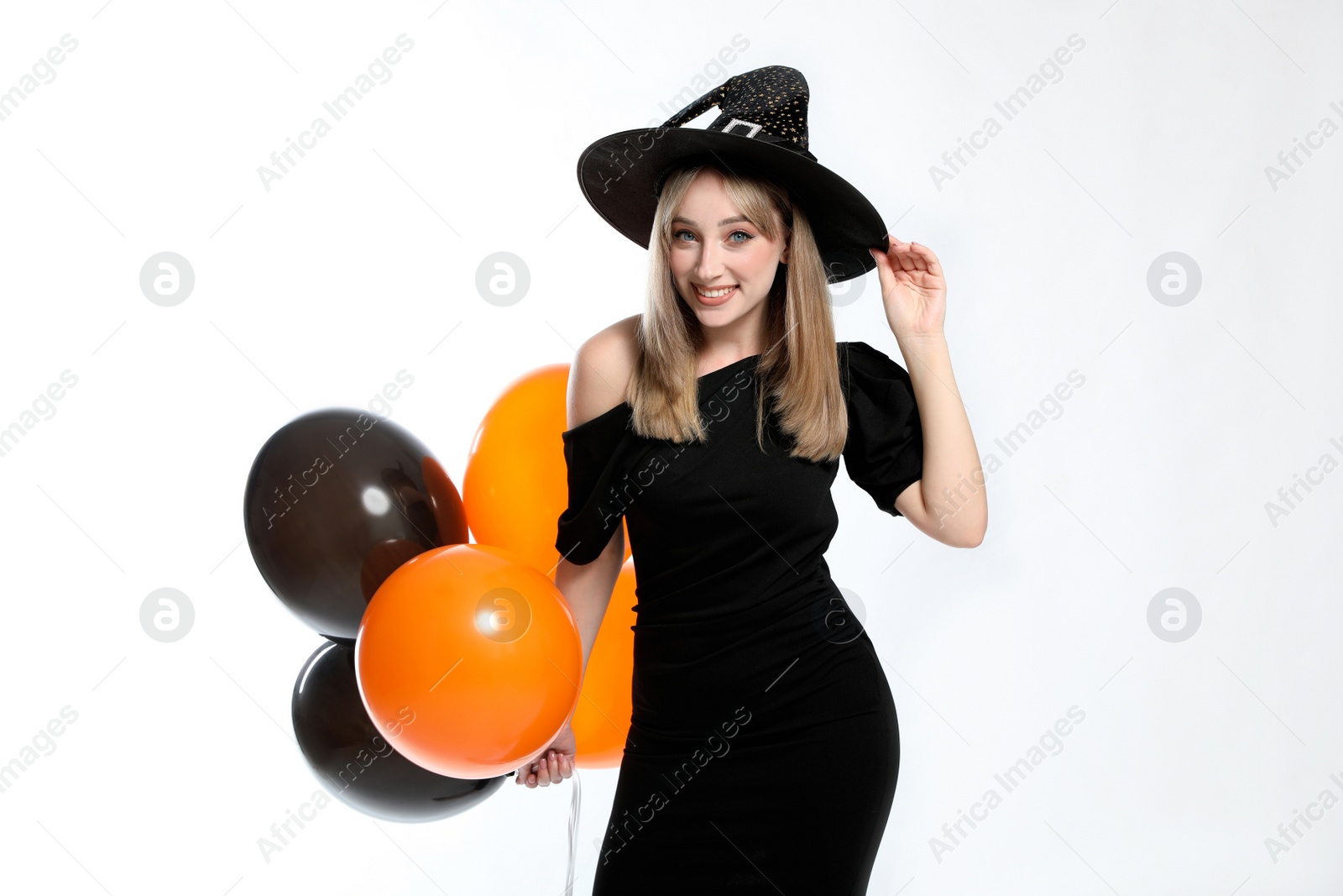 Photo of Beautiful woman in witch costume with balloons on white background. Halloween party