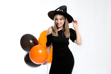 Photo of Beautiful woman in witch costume with balloons on white background. Halloween party