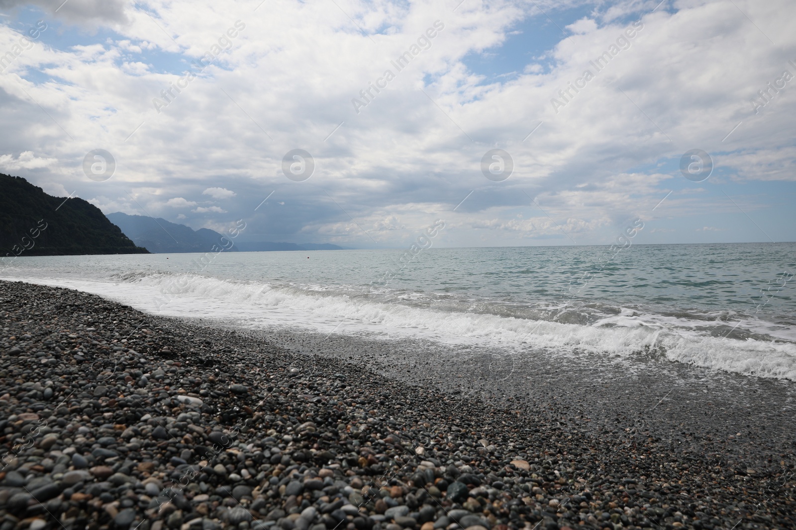 Photo of Picturesque view of beautiful sea shore and mountains under sky with fluffy clouds