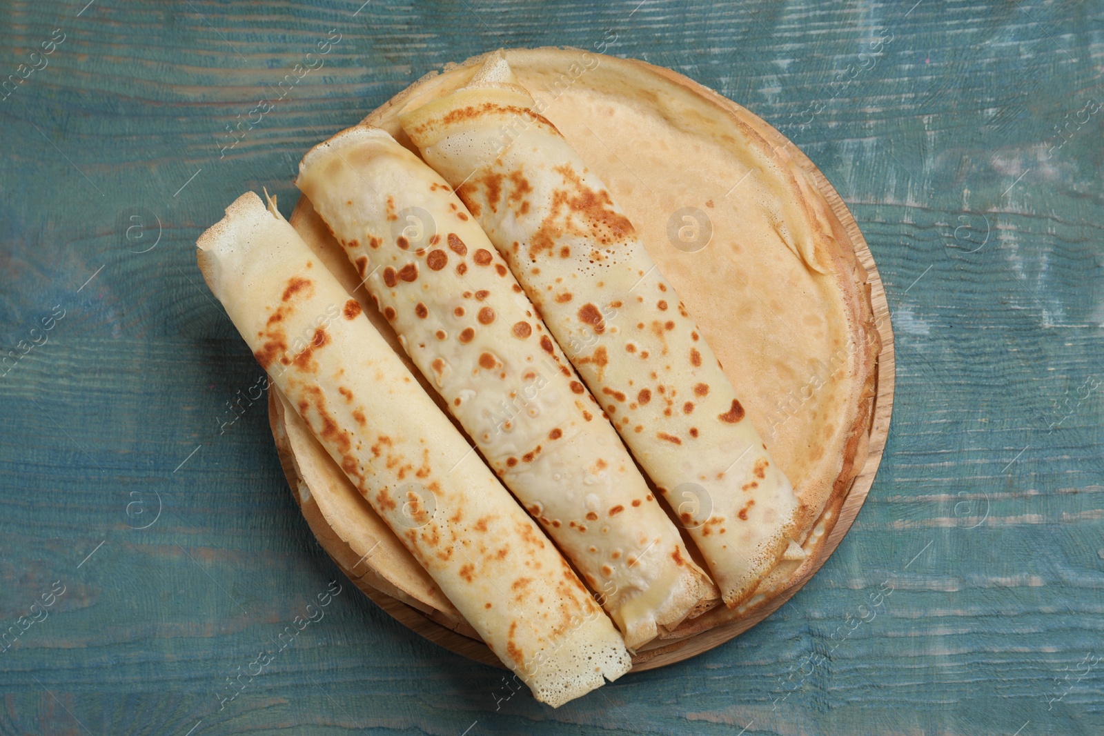 Photo of Delicious crepes on blue wooden table, top view