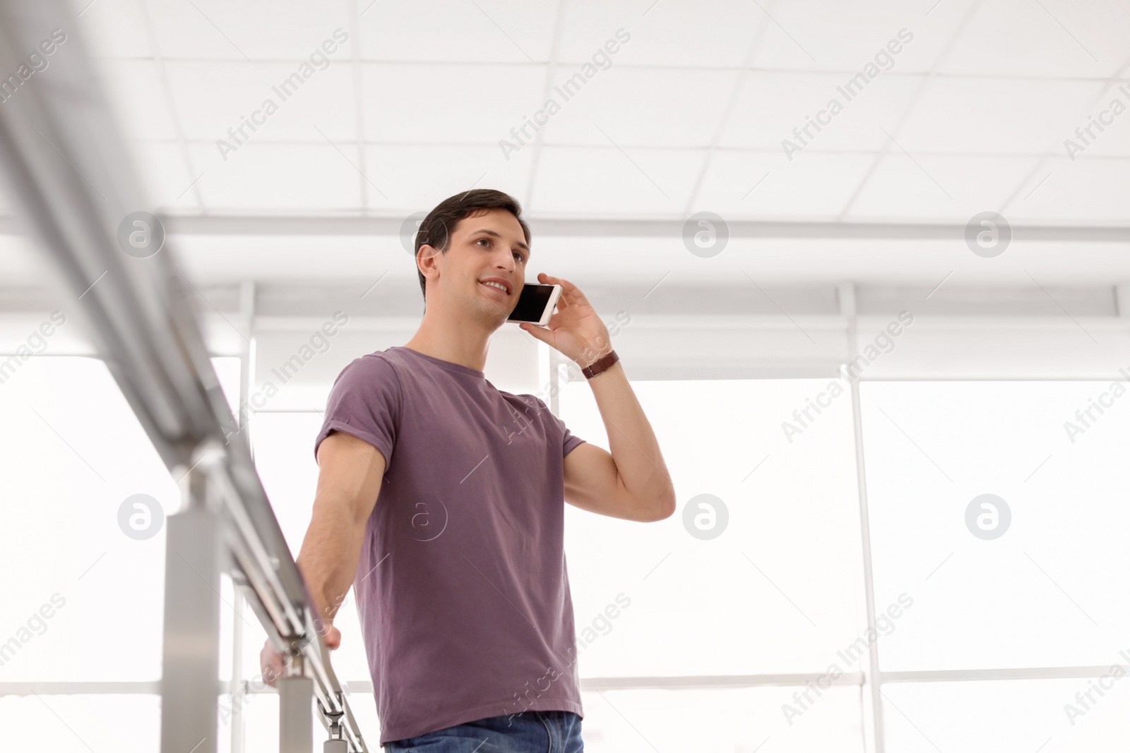 Photo of Portrait of confident young man with mobile phone, indoors