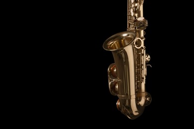 Photo of Beautiful saxophone on black background. Space for text