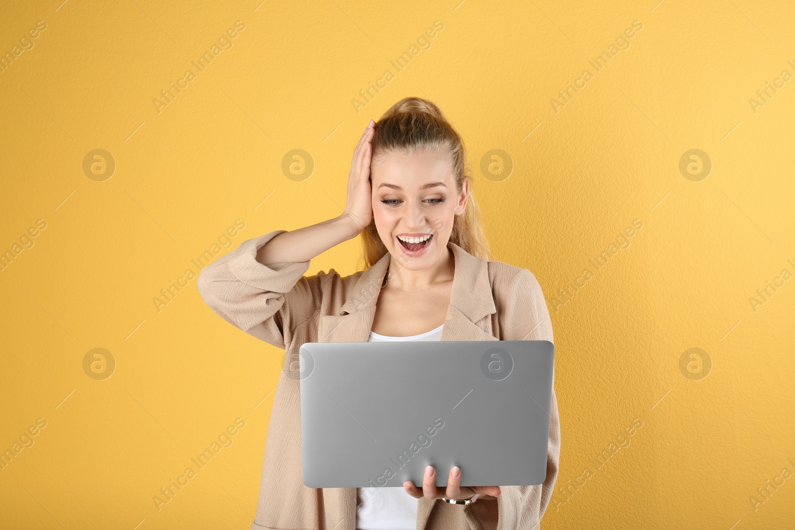 Photo of Portrait of emotional young woman with laptop on yellow background