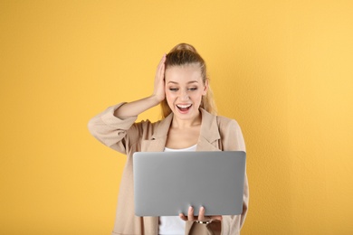 Photo of Portrait of emotional young woman with laptop on yellow background