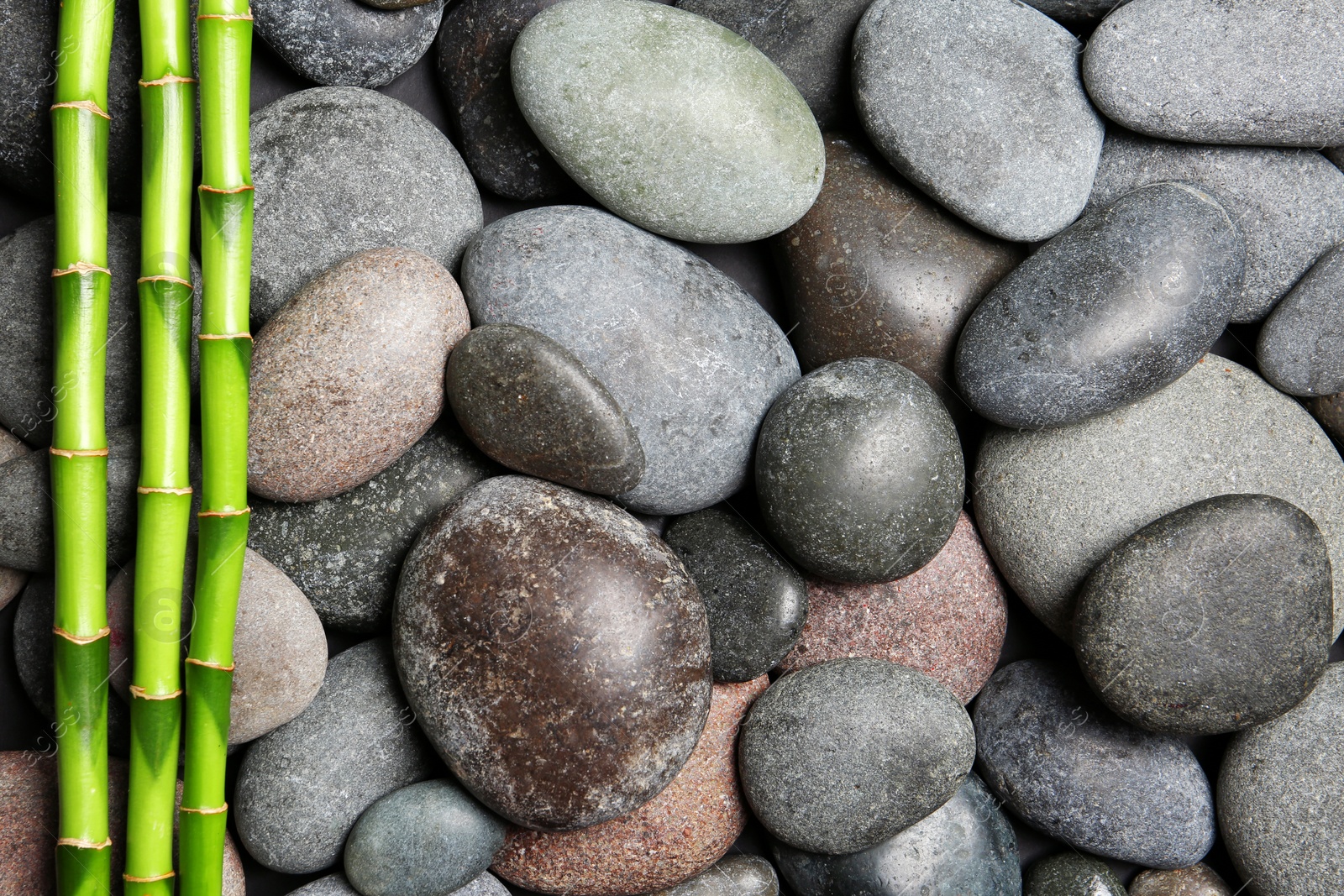 Photo of Composition with spa stones and bamboo branches as background, top view