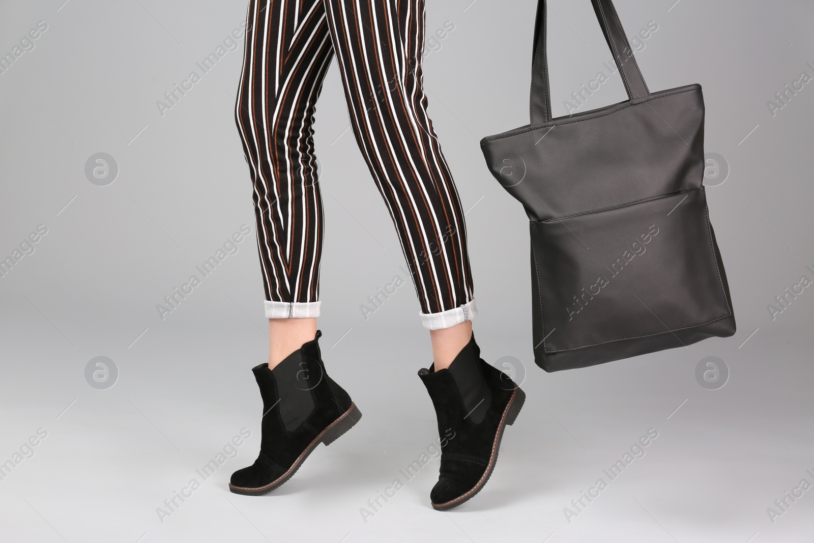 Photo of Woman in stylish shoes with bag on light background
