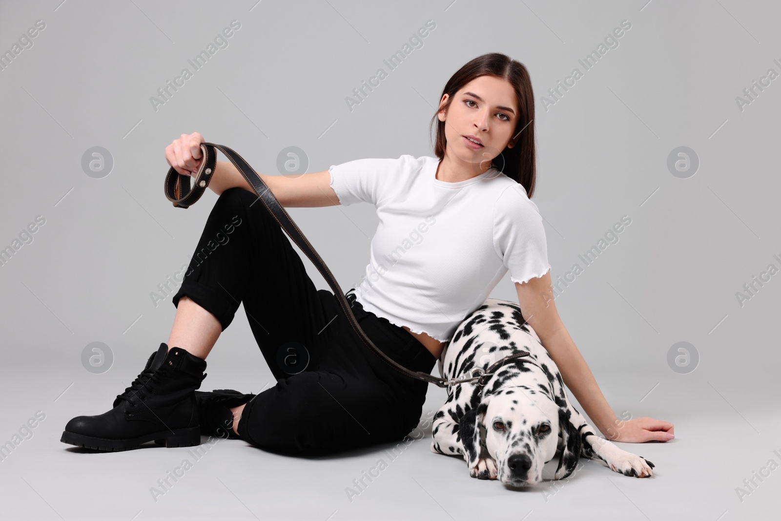 Photo of Beautiful young woman with her adorable Dalmatian dog on light grey background. Lovely pet