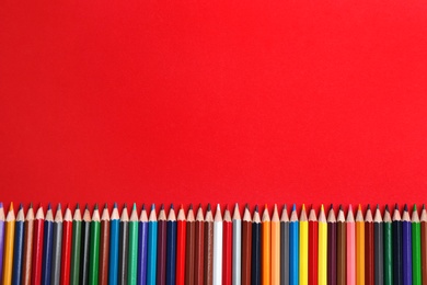 Photo of Flat lay composition with color pencils on red background. Space for text