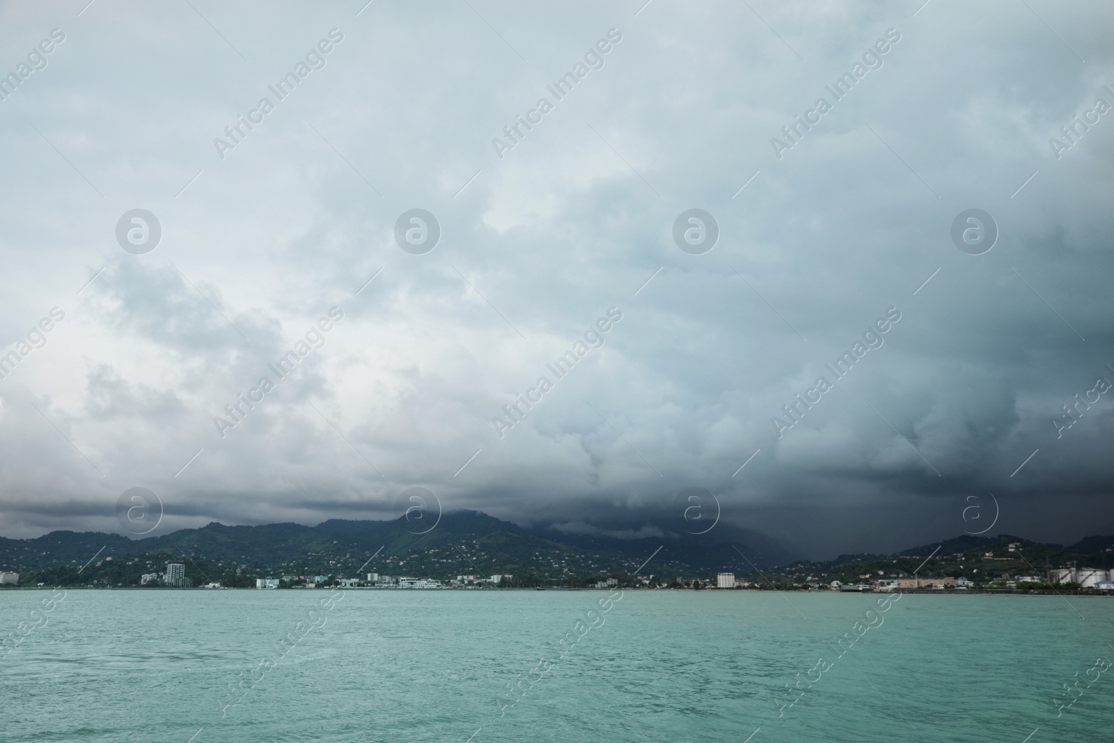 Photo of Picturesque view of sea with coastline and mountains under cloudy sky