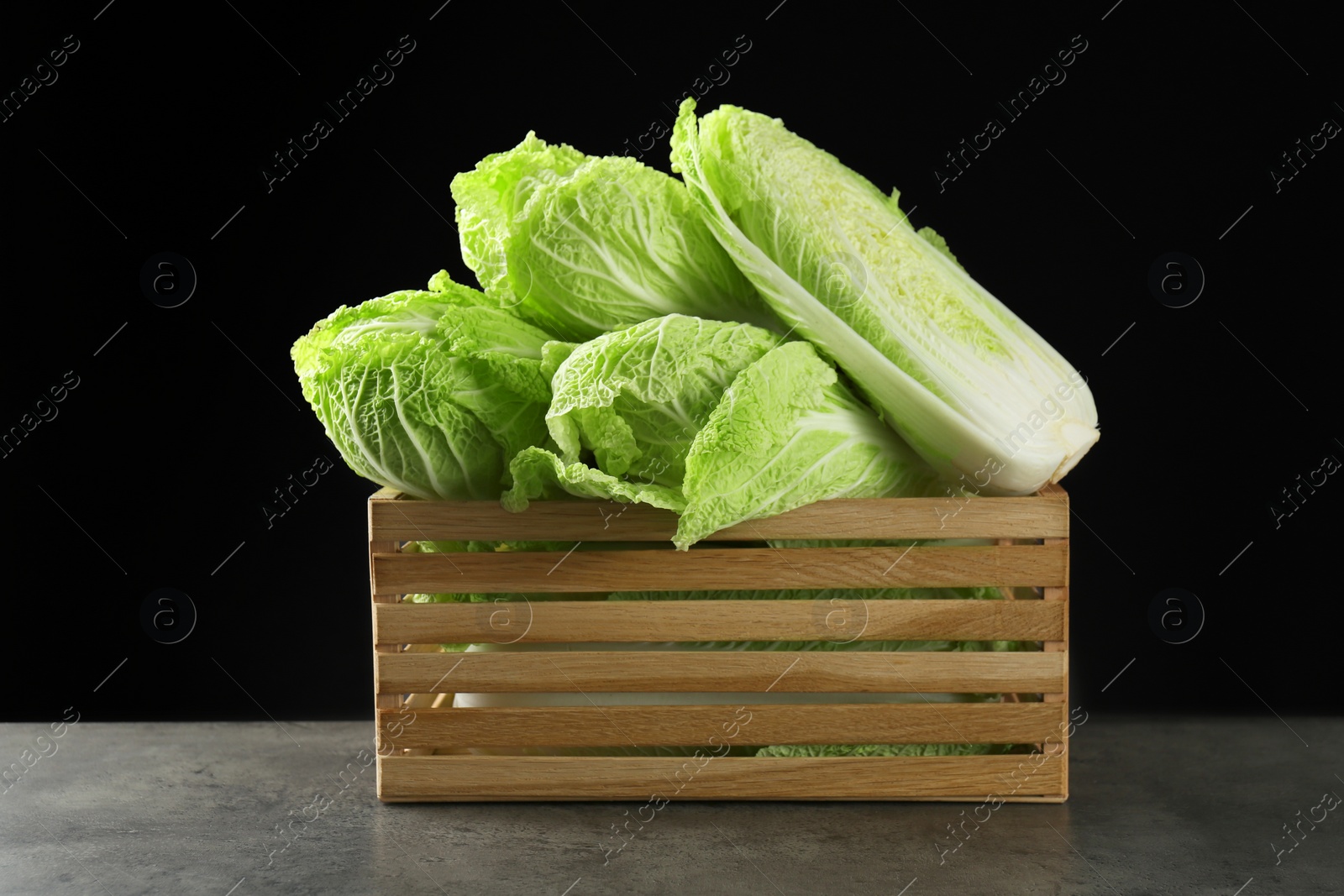 Photo of Fresh ripe Chinese cabbages in wooden crate on grey table