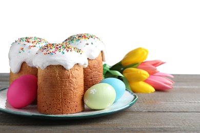 Photo of Beautiful Easter cakes, tulips and painted eggs on wooden table against white background