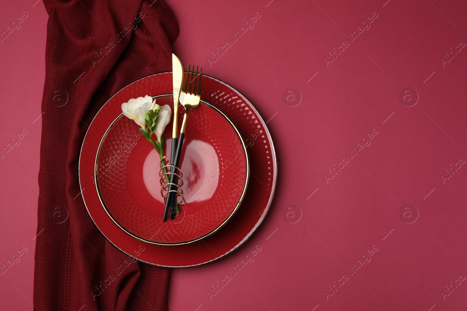 Photo of Stylish table setting with cutlery and floral decor on pink background, top view. Space for text