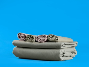 Photo of Stack of clean bed sheets on blue background