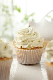 Tasty cupcakes with vanilla cream on table, closeup